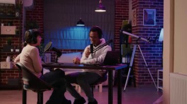 Afro-amerikan podcaster 'ı dinleyicileri akşam programında tanıtıyor. Ev stüdyosundan. Profesyonel ses araçları kullanarak çeşitli çiftler internet radyosunda canlı röportaj yapıyorlar..