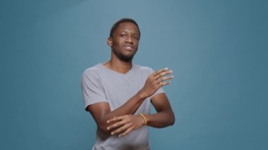 Stüdyoda kolları çaprazlanmış şekilde poz veren Afro-Amerikan bir adamın portresi. Genç adam gülümsüyor ve kendinden emin hissediyor. Olumlu bir ifadeye sahip, hırslı bir erkek model..