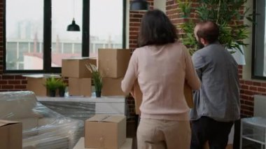 Birlikte taşındıktan sonra yeni bir daire dekore etmek için mobilya taşıyan genç evli bir çift. Eşyalarını yerleştiriyorlar. Ev sahipleri ev kredisi ve ipotekle satın alınmış..