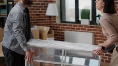 Evli bir çift, taşınmak için mobilyaları olan bir ev dekore ediyorlar. İç dekorasyon için masa taşıyorlar. Gelecek için heyecanlı olmak ve ev sahibi olarak yeni başlangıçlar yapmak. El kamerasıyla..