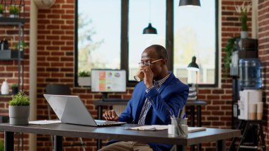 Bilgisayarında tarayıcı uygulaması olan Afrikalı Amerikalı işçiler yeni bir strateji oluşturmak için internet istatistik evrakları hazırlıyorlar. İnternet sitesinde çalışan bir işletmeci. Üçayak atışı.