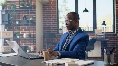 Profesyonel işadamı ofis masasındaki dizüstü bilgisayarına istatistik raporu yazıyor. Web sitesi başvurusu için evrak işleriyle uğraşıyor. Şirket çalışanlarının iş planlama projesi. El kamerasıyla..