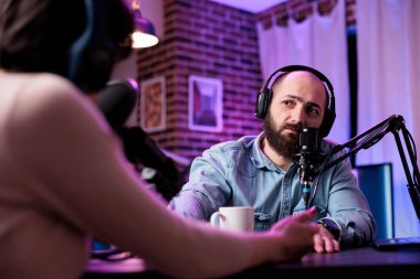 Erkek video blogcusu podcast 'te röportaj yapıyor, stüdyoda konukla konuşuyor. Genç adam sosyal medya blogcusu ile sohbet ediyor, kanal içeriği için kayıt yapıyor.