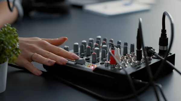 Influencer tweaking audio mixer knobs and buttons. Internet live talk show host changing volumes while using studio console equalizer to improve broadcast sound quality. Close up shoot