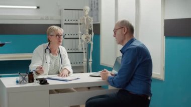 Doktor, emekli hastaya tıbbi yardım sağlamak için sağlık raporuna reçeteli ilaç yazıyor. Randevuda teşhis tedavisi için gerekli belgelere ilişkin sağlık bilgileri.