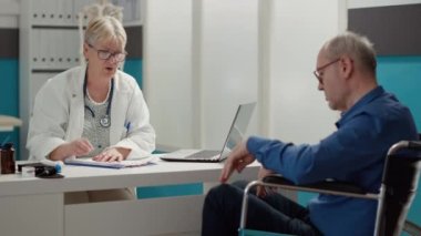 Muayene sırasında kronik sakatlığı ve sakatlığı olan kadın doktor danışmanı. Kabinede sağlık kontrolünde fiziksel sağlık durumu olan tekerlekli sandalye kullanıcısı.