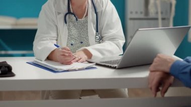 Genel pratisyen hekim, hastaya reçeteli ilaç vermek için dosyaların muayene raporlarını hazırlıyor. Kağıtlara sağlık bilgileri yazmak.