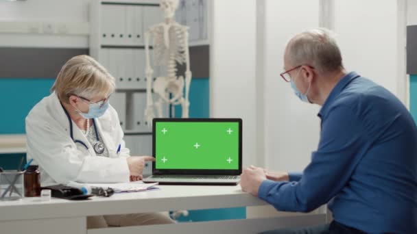 Lekarz Ogólny Pokazuje Laptopa Zielonym Ekranem Emerytowanemu Pacjentowi Maską Wizytę — Wideo stockowe