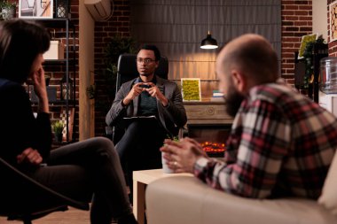 Evlilik sorunları olan bir çiftle konuşan psikoterapist anlaşmazlıkları çözmeye ve destek vermeye çalışıyor. İlişki sorunları ile ilgili psikanaliz danışmanlığı, ofiste profesyonel danışmanlık.