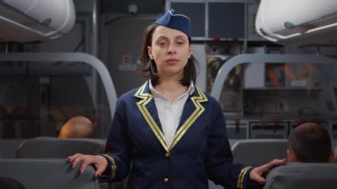 Havacılık üniformalı kadın hostes portresi insanları uçağa bindiriyor, koltuklara yardım ediyor. Uçak jeti ve uluslararası havayolu şirketinde yolcuları karşılamak için uçak koridorunda oturuyoruz..