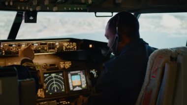 Afrika kökenli Amerikalı yardımcı pilot pilotla pilot pilot pilot pilot kokpitte, motor kolu boğazında ve yükseklik ve boylam ayarında. Kontrol panelinde yön bulma komutu. El kamerasıyla..