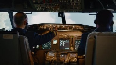 Çeşitli kaptan ve yardımcı pilot takımları kalkış ve uçak uçurmak için gösterge panelini kullanıyor. Kokpitteki kontrol panelinde yükseklik ve boylam değiştirmek için düğmelere basıyorum. El kamerasıyla..