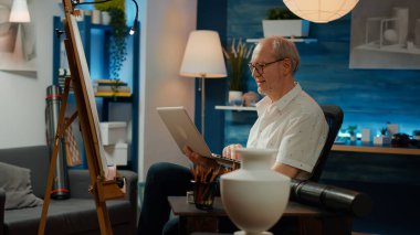 Sanatsal becerileri olan profesyonel sanat eserleri yaratmak için internetten ilham almaya çalışan yaşlı bir insan. Kalemlerle özgün bir taslak çizmek için bilgisayarda şaheser modeli aranıyor.