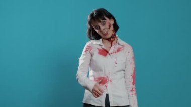 Korkunç görünümlü canavar mavi arka planda el hareketi gösteriyor. Korkunç beyin yiyen, yürüyen, derin ve kanlı yaraları olan ölü bir cesedi onaylamak onaylanmış el işareti göstergesidir. Stüdyo çekimi