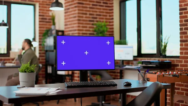 Empty office desk with greenscreen display on computer desktop, isolated chroma key background with mockup template. Monitor with blank screen used by business people in startup office.