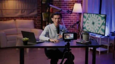 Asian vlogger recording online video for podcast show, filming episode on camera for internet channel. Live broadcasting vlog and talking to social media audience, creating content.