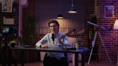 Podcast ekipmanlarıyla video çekerek sosyal medya kanalı için canlı içerik yaratıyor. Ses istasyonunda talk show prodüksiyonuyla kayıt bölümü, profesyonel yayın.