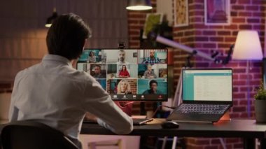 Asyalı erkek serbest yazar, bilgisayardaki uzaktan telekomünikasyon video konferansını kullanarak evdeki video görüşmesinde sohbet ediyor. Sanal telekonferans ve tele-çalışma sohbeti üzerine meslektaşlarımla konuşuyorum..