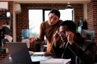 İnternet sitesi uygulamasını bilgisayarında analiz eden iş adamı, maluliyet dostu ofiste iş arkadaşıyla çalışıyor. Sağlık sorunu olan erkek tekerlekli sandalye kullanıcısı takım çalışması stratejisi uyguluyor..