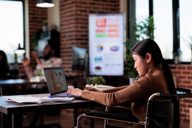 Engelli bürosunda çalışan felçli serbest çalışan, fiziksel sağlık sorunu olan biri. İnternet sitesini taramak için dizüstü bilgisayar kullanan kadın tekerlekli sandalye kullanıcısı.