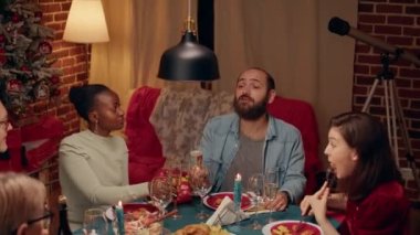 Çeşitli insanlar kış tatilini geleneksel yiyecek ve alkolle kutlarken buluşmanın keyfini çıkarıyorlar. Mutlu aile üyeleri evde Noel yemeği masasında otururken şampanya içiyor.