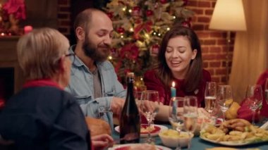 Mutlu insanlar evdeki Noel yemeğinin tadını çıkarırken birbirleriyle konuşuyorlar. Neşeli aile fertleri, Noel tatili kutlaması için Xmas 'ın otantik süslemeleriyle rahat bir dairede..