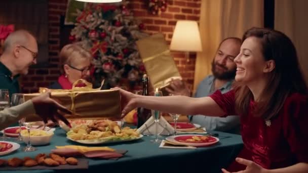 Festive Family Members Sitting Christmas Dinner Table While Exchanging Presents — Vídeos de Stock