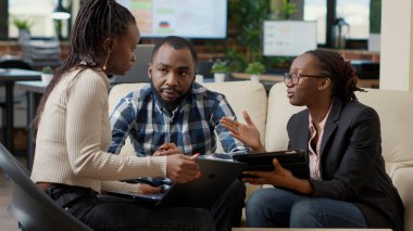 Haritalardaki mali istatistikleri analiz eden bir grup meslektaşım iş projesi yaratmak için araştırma stratejisi planlıyorlar. Ofis çalışanları dijital tablet ve dizüstü bilgisayarla kanepede takım çalışması yapıyor..