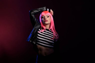 Arka planda koyu pembe bir gölgeyle poz veren kendine güvenen genç, şık ve modaya uygun olmak için rockçı deri ceket giyiyor. Punk tarzı olan modern çekici insan kameraya bakıyor..