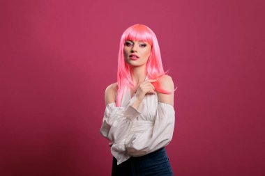 Kendine güvenen, modaya uygun moda ikonu gibi davranan zarif oyun kıyafetleri giyen ve pembe saçlı bir kadın. Seksi makyajlı sevimli çekici kız kameraya bakıyor, eğleniyor..