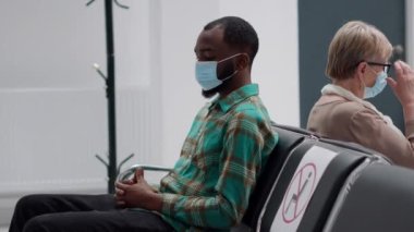 Hastane resepsiyonunda yüzü maskeli çok ırklı hastalar sağlık uzmanlarıyla randevularına başlamak için bekliyorlar. İnsanlar covid 19 salgını sırasında danışmanlık yapıyorlar..
