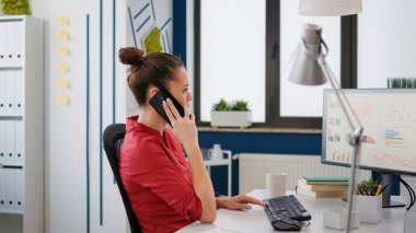 Yönetici danışmanı aramak için akıllı telefonu kullanıyor. İstatistik çizelgeleriyle iş ortaklığı yapıyor. İş geliştirme için çalışan telefonda konuşuyor..