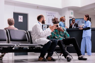 Servikal yakalı yaralı hasta bekleme odasının lobisinde doktorla konuşuyor. Boyunluk takan yaralı bir adam kaza yaralarını tedavi etmeye çalışıyor, tedavi görüyor..