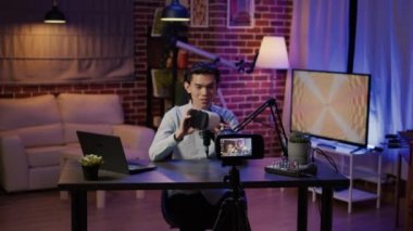 Erkek vlogger video yayınında VR gözlükleriyle ürün incelemesi yapıyor, 3D simülasyonlu sanal gerçeklik kulaklığı hakkında konuşuyor. Canlı yayında modern gözlük tavsiye ediliyor..