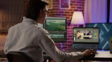 Asyalı kameraman ekrandaki görsel efekt yazılımını kullanarak bilgisayar üzerinden multimedya film görüntülerini düzenliyor. Renk derecelendirme ile video montajında renk düzeltmesi yapmak, içerik yaratmak. Üçayak atışı.