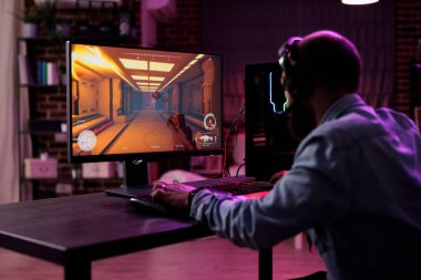 Content creator having fun with video games play competition, using computer to stream online championship. Male gamer playing rpg action tournament game at desk with neon lights.