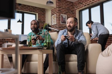 Happy people doing teamwork and playing strategy video games on tv, enjoying leisure activity at fun house party gathering. Group of friends relaxing with online competition on television.