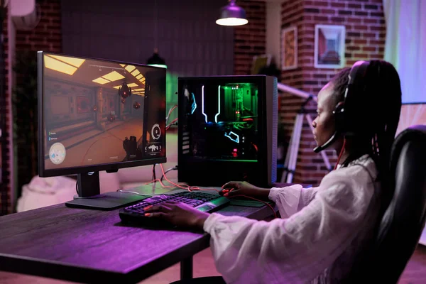 African american woman playing video games championship on online stream. Female gamer having fun with action gaming tournament, streaming virtual gameplay competition on computer.