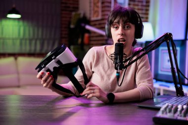 VR gözlüklerini inceleyen nüfuzlu şahıs görüntüsü. Ürün tavsiyesi için video kaydediyor. İçerik yaratıcısı, stüdyoda podcast ekipmanlarıyla sanal gerçeklik kulaklığından bahsediyor..