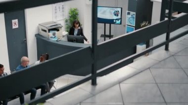 Lady receptionist working at hospital reception desk to help patients with medical appointment. Healthcare employee in waiting room lobby, checkup visit report with medication.