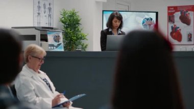 Portrait of hospital receptionist working at administrative counter to help patients with appointments. Female secretary giving support for healthcare at reception desk facility.