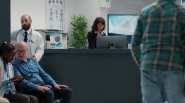 Kadın resepsiyonist, hastalara sağlık hizmetleri randevusu için uzman ile tıbbi rapor doldurmalarında yardımcı oluyor. Hastane resepsiyonunda muayene için bekleme salonu..