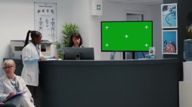 Hospital reception desk with greenscreen on tv monitor in waiting room lobby. Isolated chroma key background with blank copyspace and mockup template on display, medical facility.