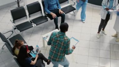 Hastane resepsiyonunda konuşan ve yazan çeşitli tıp ekipleri, hasta hastaları desteklemek için sağlık sisteminde çalışıyorlar. Bekleme odasının lobisinde randevular.