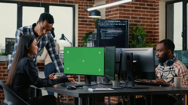 Two software developers analyzing source code looking at green screen chroma key mockup with coworker sitting at desk writing algorithm. Software developers working on artificial intelligence project.