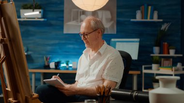 Erkek sanatçı, profesyonel sanat tasarımı çizmek için ders kitabı ve vazo modeli üzerine notlar alıyor. Not defteri ve sanatsal beceriler kullanarak modern sanat eskizini ilham alarak çizmek.