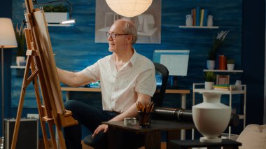 Erkek sanatçı, tuvale resim çizmek için yaratıcılık araçları ve tasarım ilhamı kullanarak kalemlerle resim çiziyor. Profesyonel becerileri ve modern sanat fikri olan bir vazo çizimi..