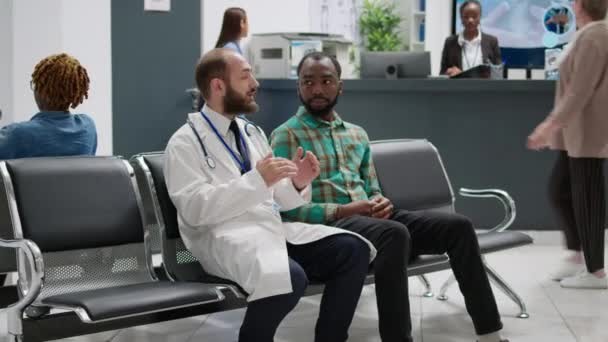 Lekarz Rozmawia Afroamerykaninem Recepcji Szpitala Robi Badania Kontrolne Poczekalni Różnorodne — Wideo stockowe