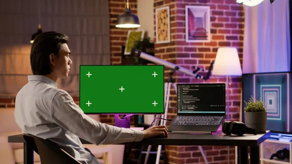 Office employee analyzing greenscreen on computer monitor at home desk. Using blank chroma key template with isolated mockup background and copyspace display, pc program. .