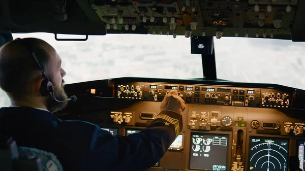 Airplane pilot flying aircraft fixing altitude and longitude level, using plane dashboard command to takeoff. Switching power engine and navigation on control panel.